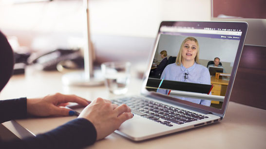 Employees attentively watching an internal company training video on a laptop in a collaborative office environment